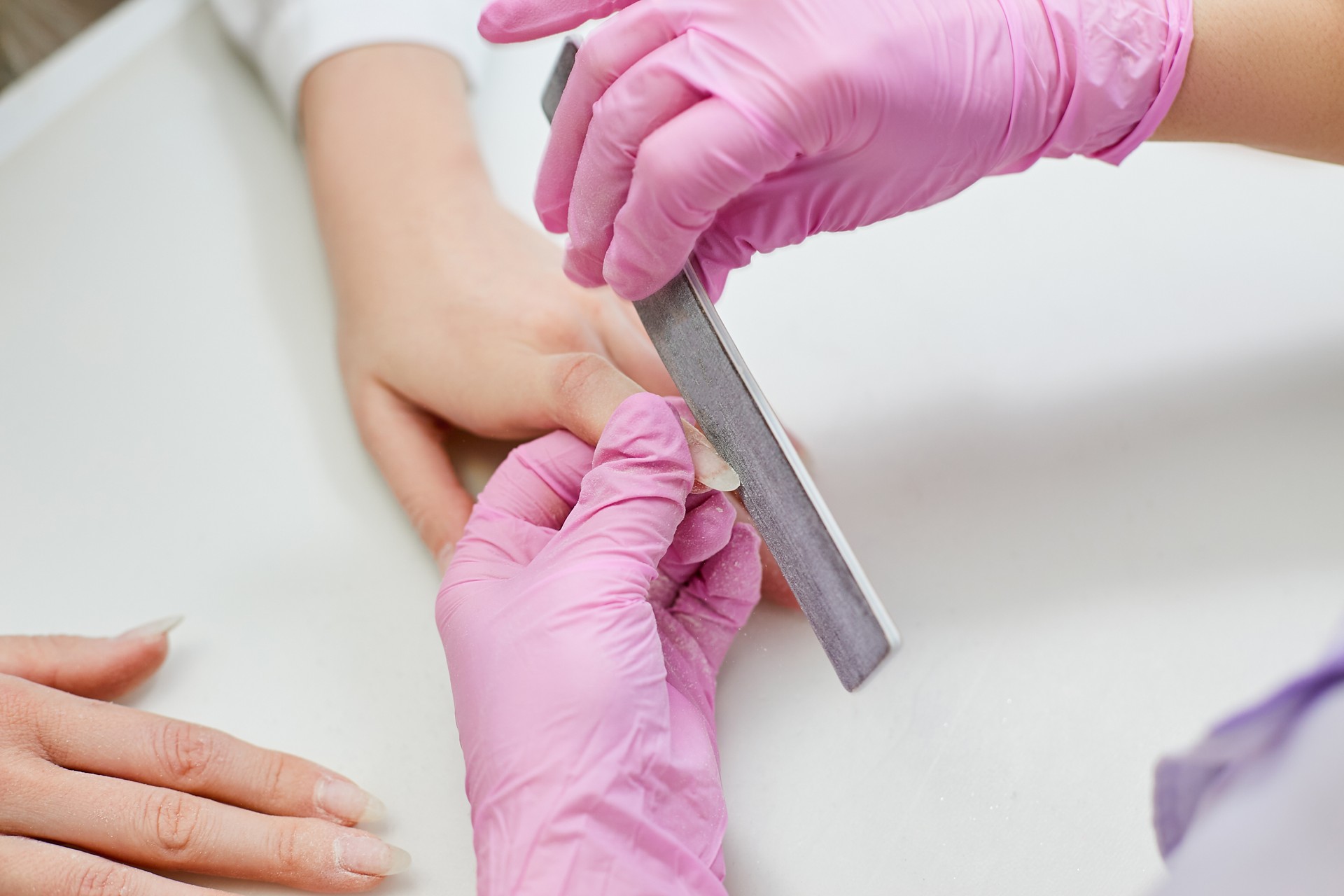 Master polishes the nails of the girl with a nail file